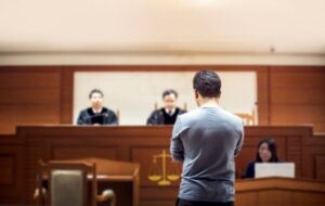 Defendant standing in front judges in court.