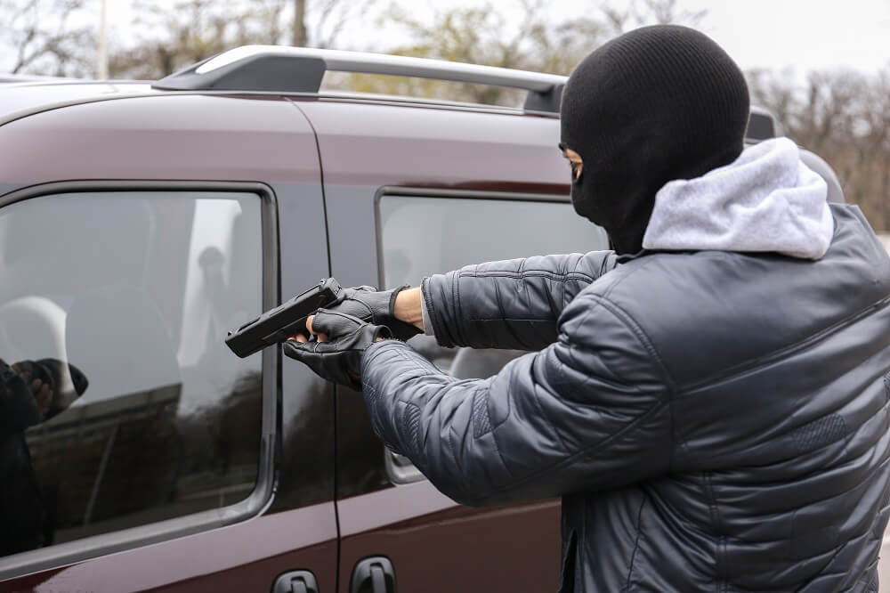 Carjacker pointing gun to driver.